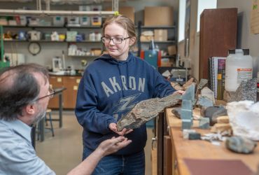 University of Akron student examines a rock sample with a faculty member in a geology lab.